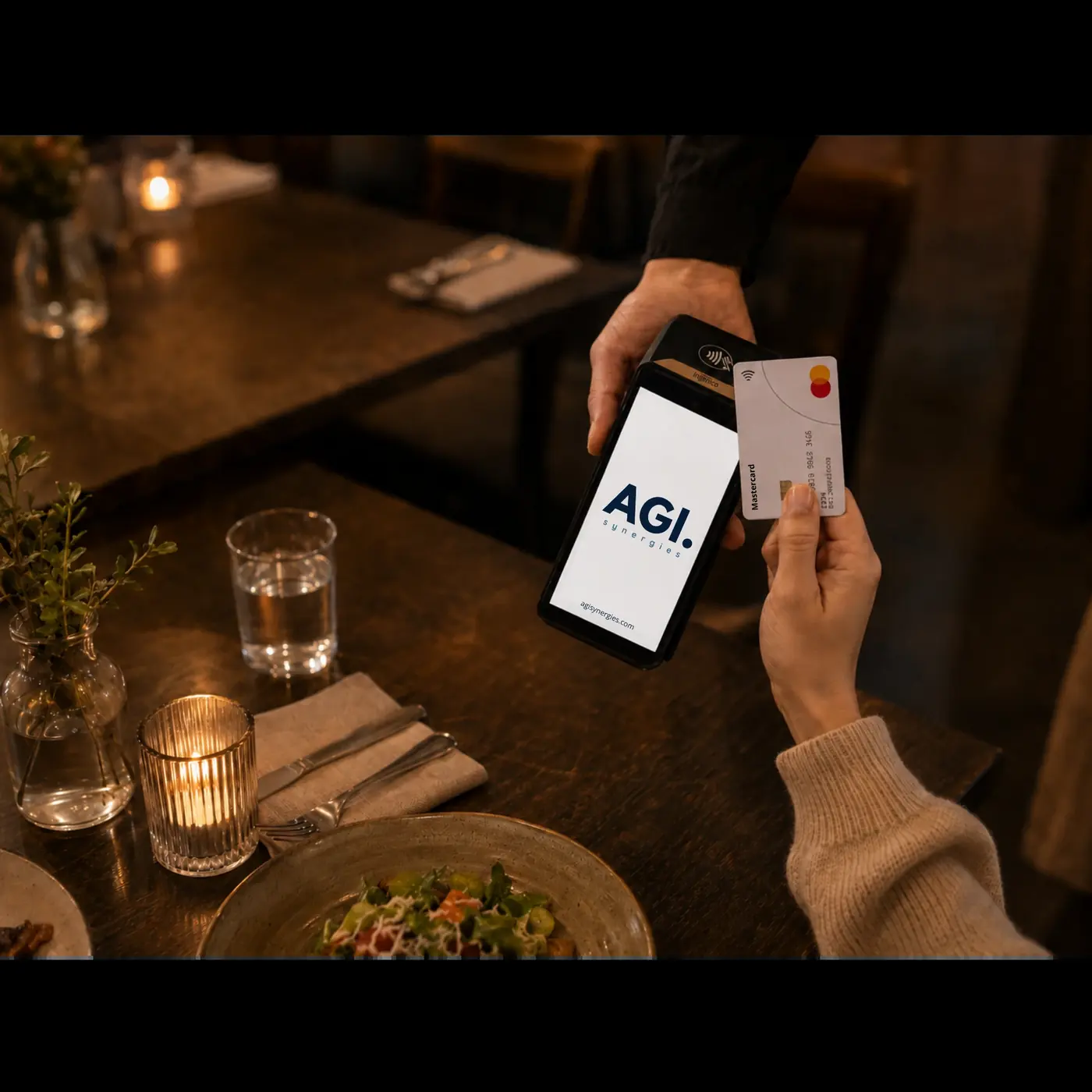 Gjest holder et kontaktløst kort mot betalingsterminalen som rekkes fram ved bordet