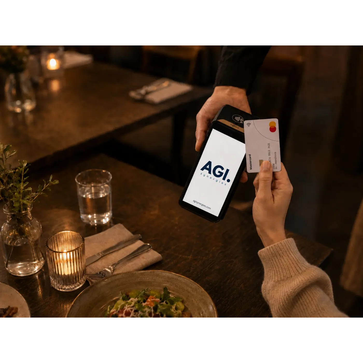 Gjest holder et kontaktløst Mastercard mot betalingsterminalen som rekkes fram ved bordet i en restaurant