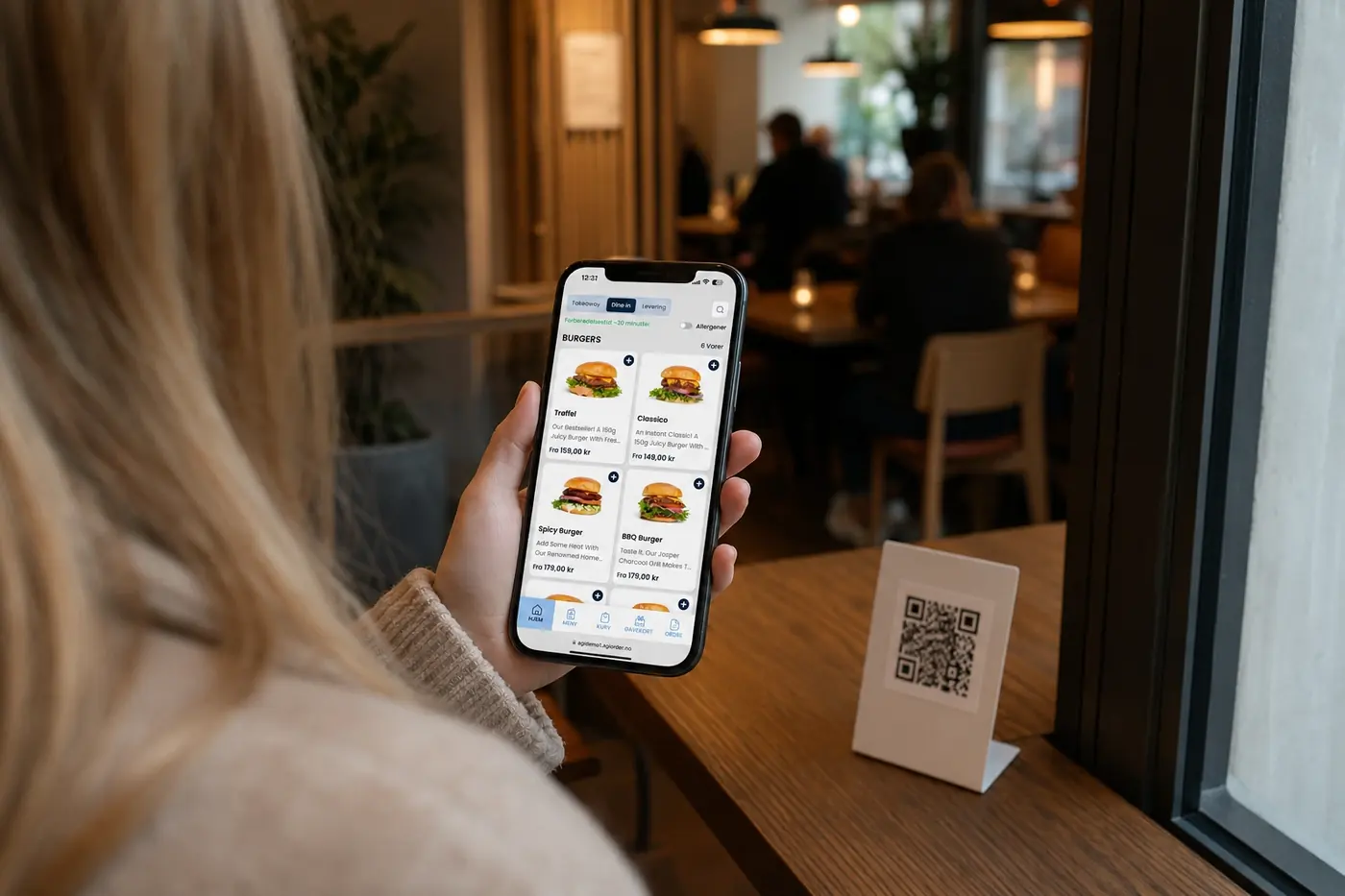 Gjest med takeaway-menyen i AGI Order på mobilen — QR-kode på bordet i kaféen